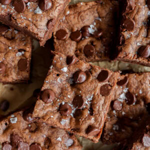pile of chocolate chocolate chip cookie bars on brown parchment paper
