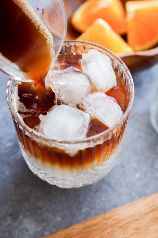 pouring espresso into glass to make an espresso tonic