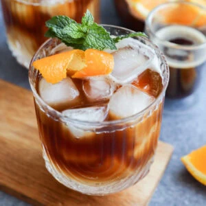espresso tonic in glasses with mint garnish and orange peel