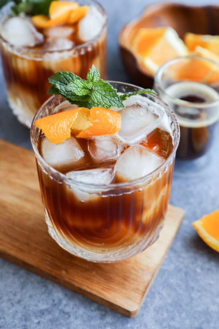 espresso tonic in glasses with mint garnish and orange peel
