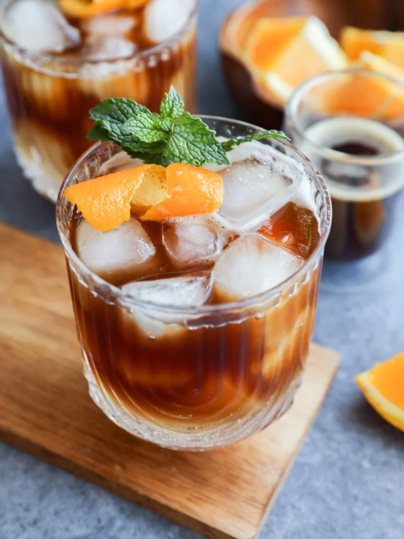espresso tonic in glasses with mint garnish and orange peel