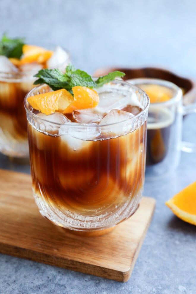 espresso tonic in glasses on wood cutting board with espresso in glass behind