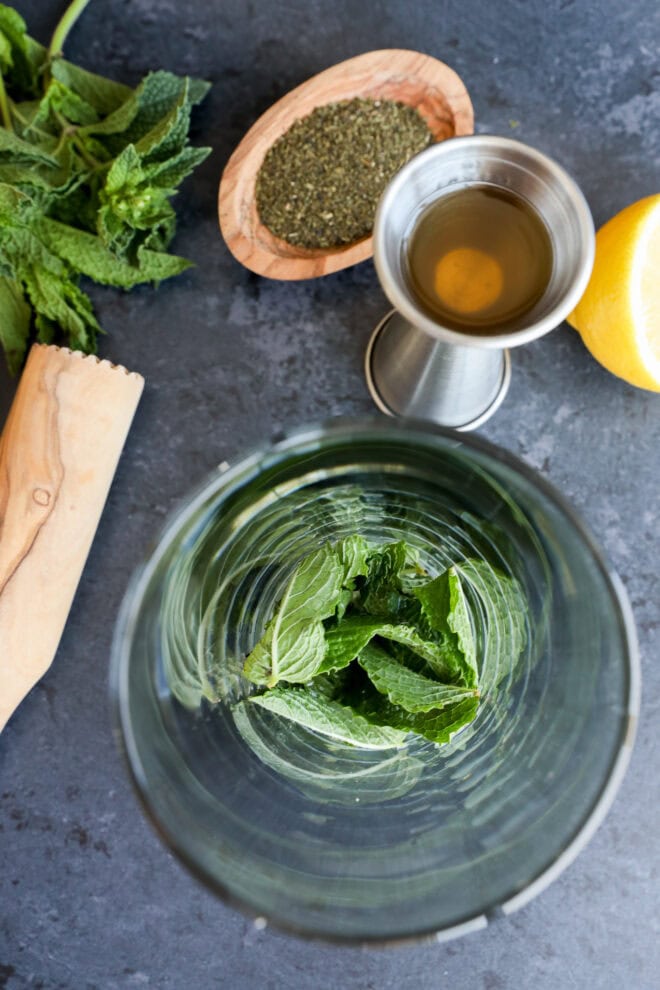Mint leaves in shaker with lemon juice and simple syrup