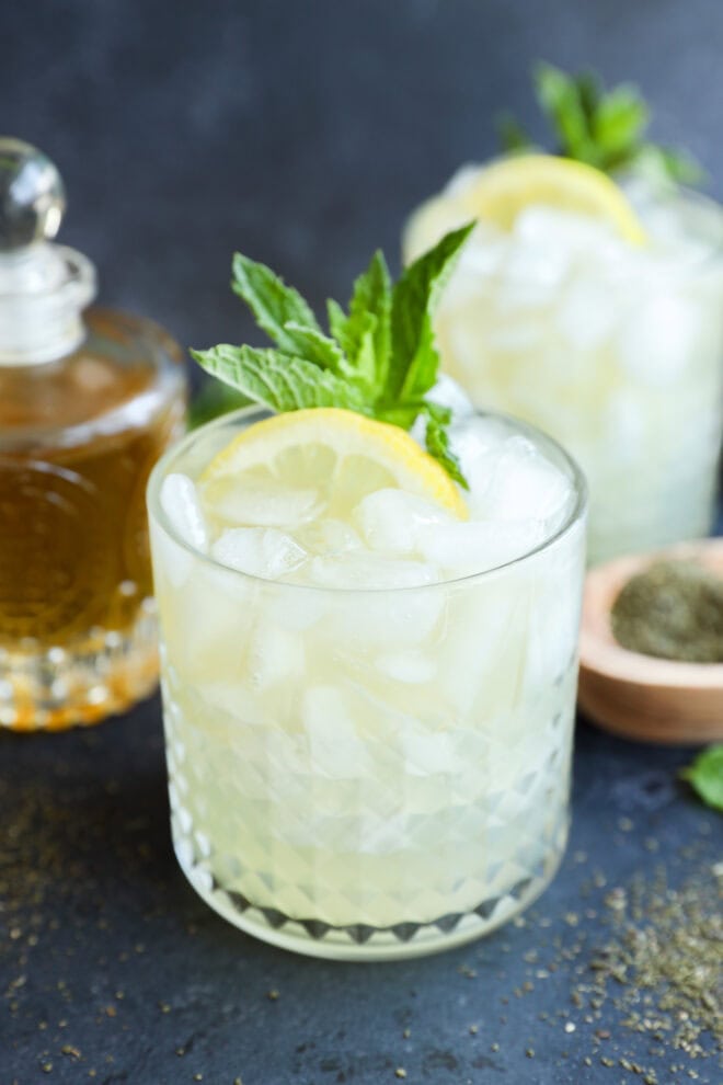 green tea cocktail in rocks glass with syrup in back and green tea