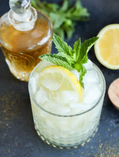 Green tea cocktail in rocks glass with lemon half and fresh mint