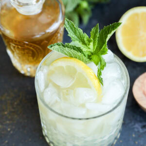 Green tea cocktail in rocks glass with lemon half and fresh mint