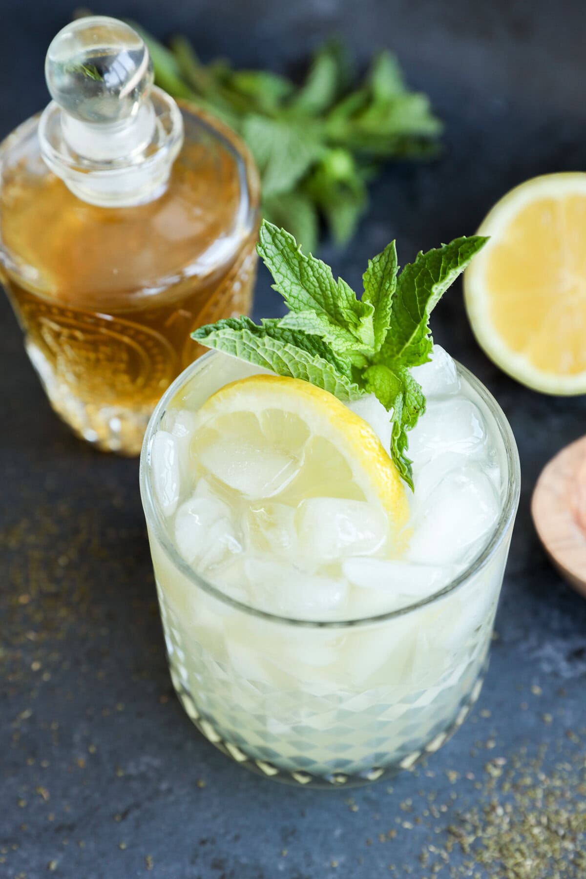 Green tea cocktail in rocks glass with lemon half and fresh mint