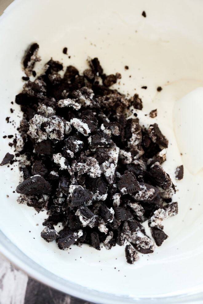 Ice cream base in large mixing bowl with pile of crushed Oreos