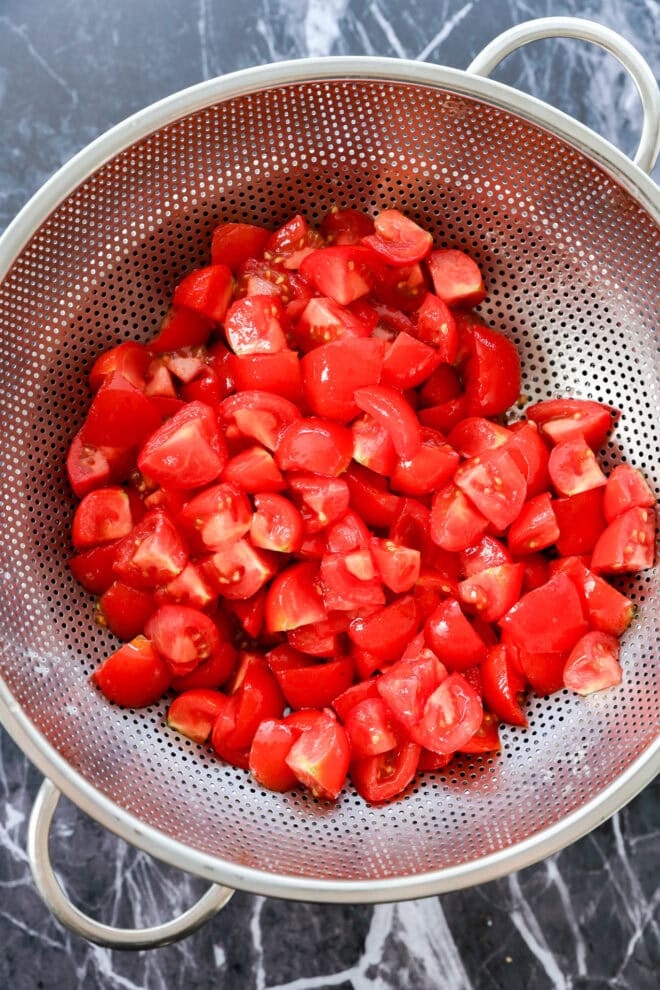 chopped tomatoes in colander draining over a bowl