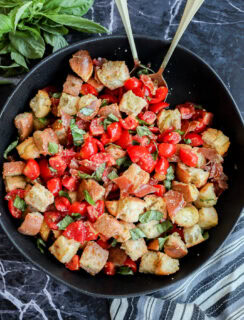 Panzanella Toscana in large black serving bowl with striped linen and fresh basil