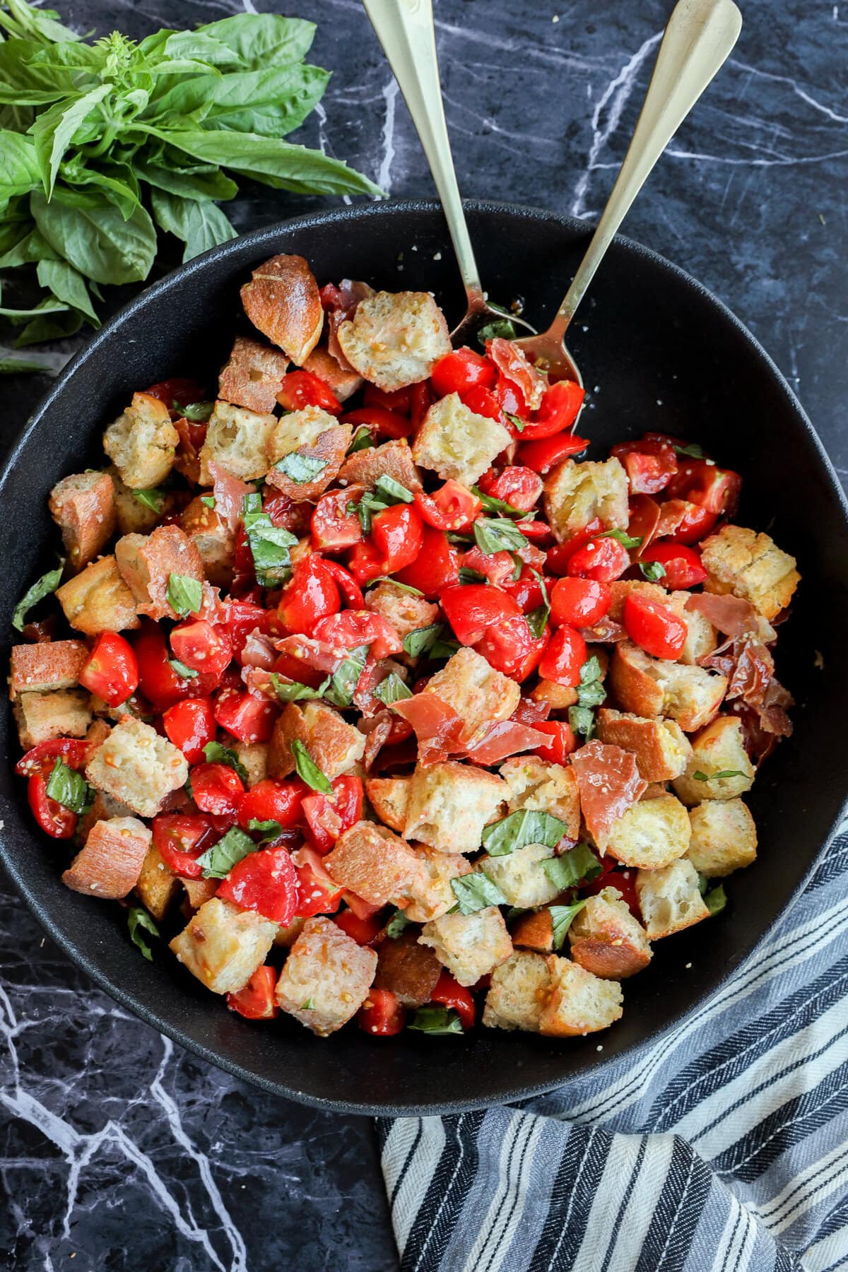 Panzanella Toscana in large black serving bowl with striped linen and fresh basil