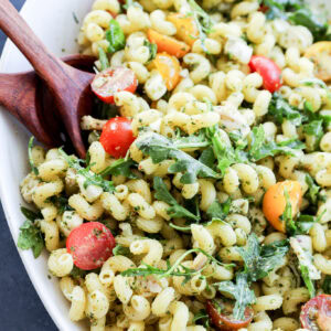 close up of pasta tossed with pesto and other fresh ingredients