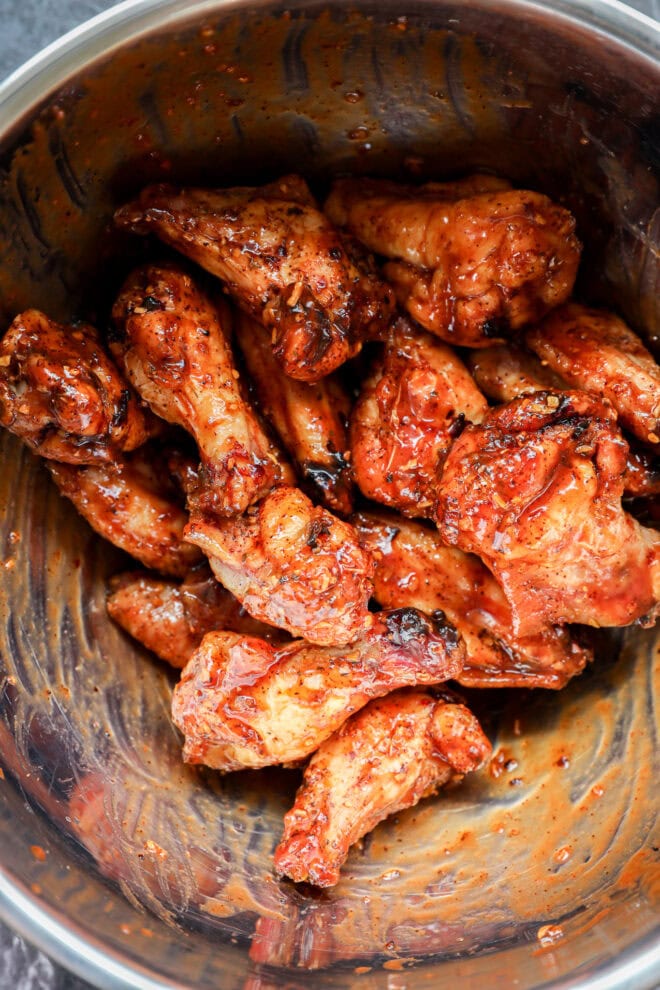 smoked chicken wings in large bowl tossed with bbq sauce