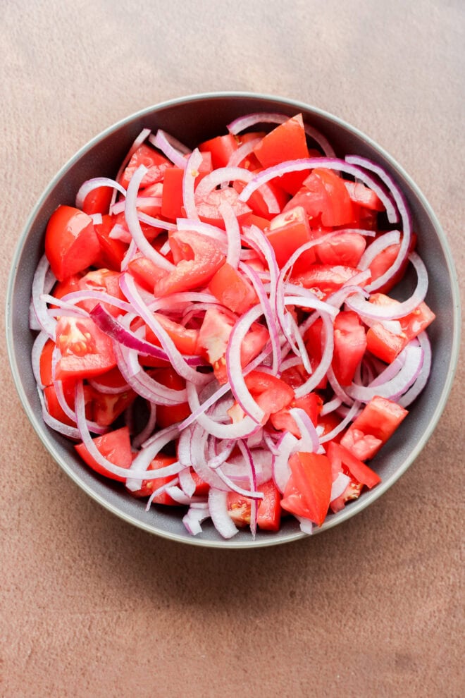 making Tomato onion salad in a bowl before pouring on dressing