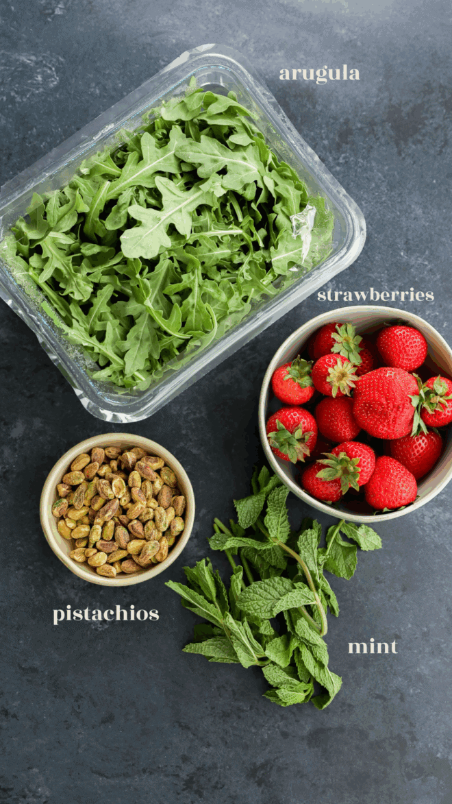 arugula strawberries pistachios and mint in bowls with text labels for salad ingredients