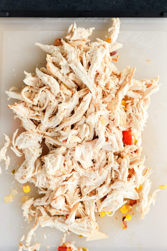 Shredded cooked chicken on a white cutting board