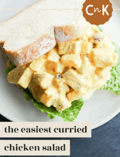 A plate with curried chicken salad on crisp lettuce, topped with two slices of bread. Text on the image reads, the easiest curried chicken salad, and a brown badge displays CnK.