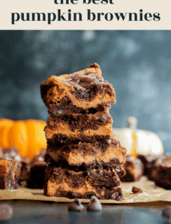 A stack of pumpkin brownies with swirled chocolate and pumpkin layers on parchment paper, with chocolate chips and small pumpkins in the background. Text reads the best pumpkin brownies and www.cakenknife.com.