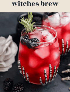 A red cocktail with ice, blackberries, and rosemary is served in a glass adorned with a silver skeleton hand. A white rose and blackberries sit nearby. The text reads witches brew and www.cakenknife.com.