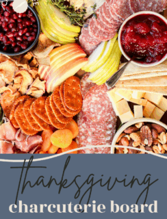 A colorful Thanksgiving charcuterie board with sliced meats, cheese cubes, apple and pear slices, crackers, dried fruit, pomegranate seeds, and cranberry sauce arranged on a wooden board. The perfect festive Thanksgiving charcuterie board for your celebration.