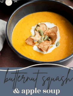 A bowl of creamy butternut squash and apple soup is topped with a swirl of cream, dried apple slices, and pumpkin seeds. The text on the image reads “butternut squash & apple soup.”.