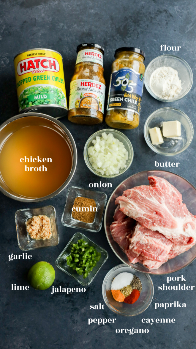 Top-down view of pork green chile ingredients, featuring chicken broth, chopped green chiles, salsa verde, flour, onion, butter, pork shoulder, garlic, lime, jalapeño, and assorted spices arranged in small bowls.