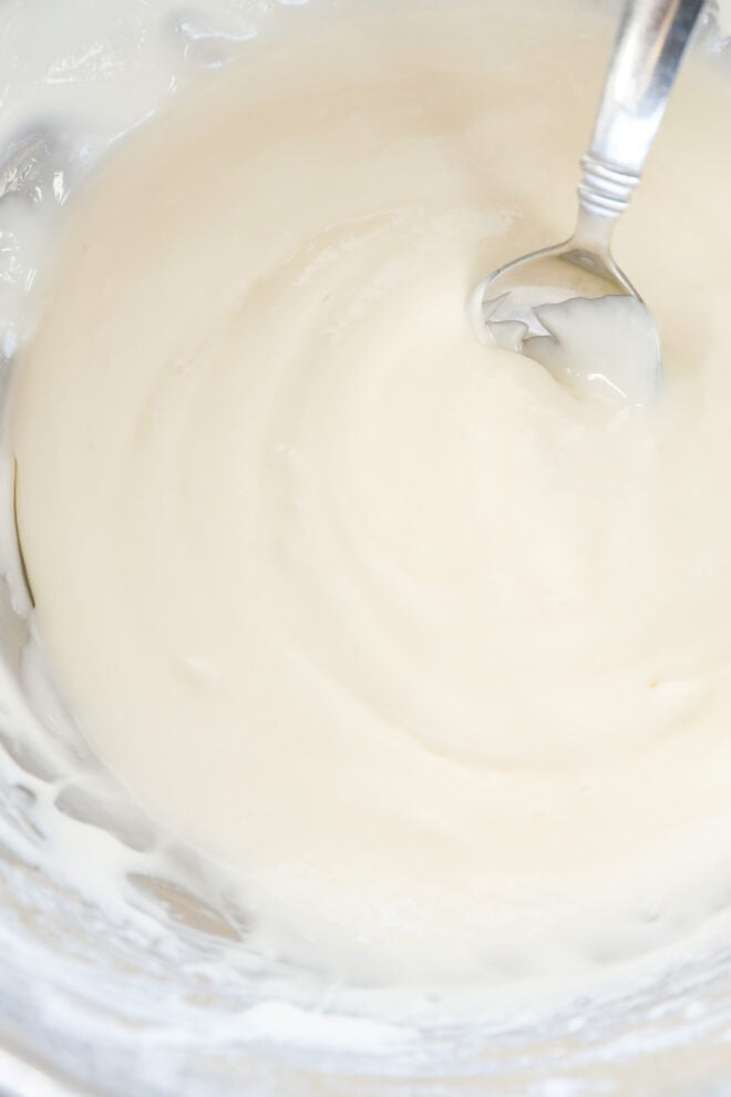 A close-up of a bowl filled with smooth, creamy white icing