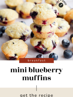 A stack of Mini Blueberry Muffins is surrounded by fresh blueberries on a white surface. Text reads, breakfast: Mini Blueberry Muffins, get the recipe.