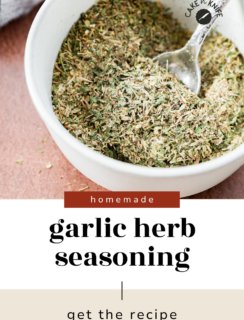 A white bowl filled with aromatic garlic herb seasoning and a spoon, with text reading homemade garlic herb seasoning—get the recipe.