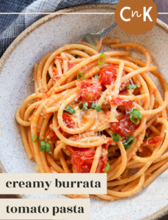 A bowl of creamy burrata pasta with chili crisp & burst tomatoes, featuring sweet cherry tomatoes, grated cheese, and chopped green onions, served with a fork. Text reads creamy burrata tomato pasta.