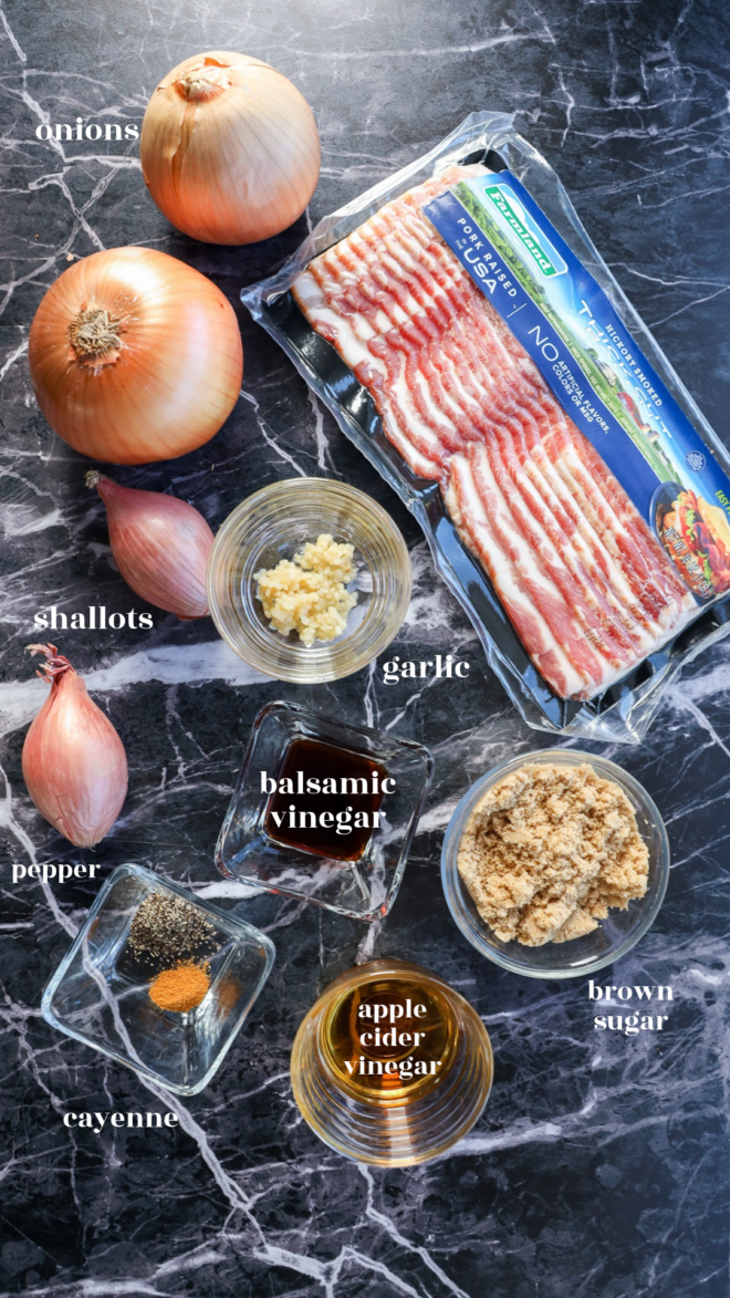Ingredients for Bacon Onion Jam arranged on a dark marble surface: bacon, onions, shallots, minced garlic, balsamic vinegar, brown sugar, apple cider vinegar, black pepper, and cayenne.