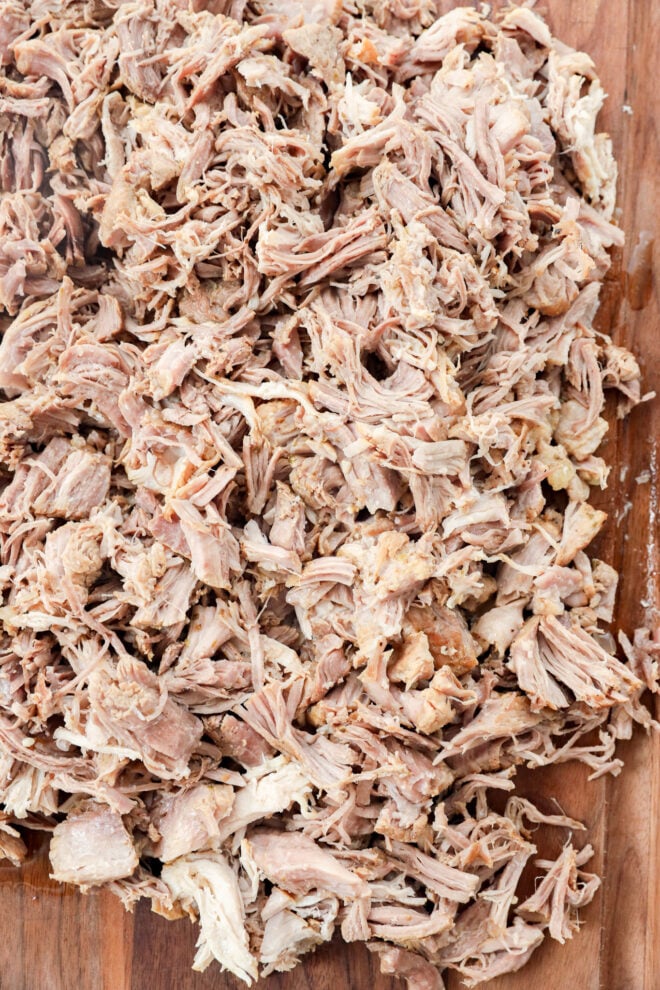 A pile of shredded pork instant pot carnitas on a wooden cutting board.