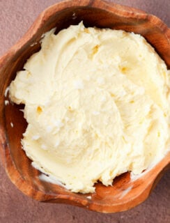 A wooden bowl filled with swirled butter topped with flakes of sea salt.