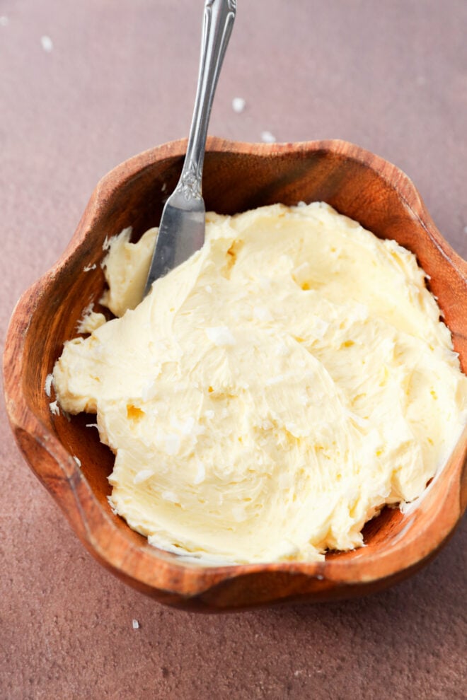 Softened butter with sea salt in a wooden bowl with a metal spreader.